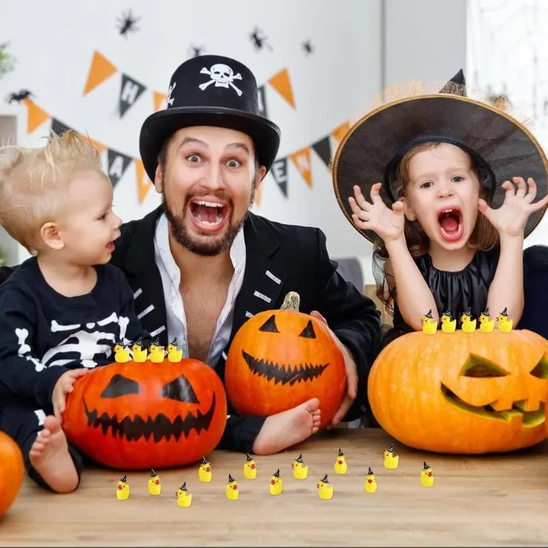 A man and a girl are posing with carved pumpkins and miniature resin witch hat ducks on a wooden table.