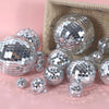 Silver disco mirror balls scattered on a pink surface with a woven basket background