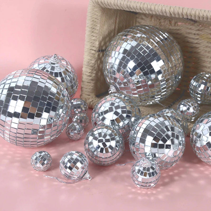 Silver disco mirror balls scattered on a pink surface with a woven basket background