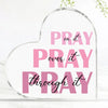 A clear acrylic heart-shaped sign with pink text that reads Pray on it Pray over it and Pray through it