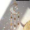 A handcrafted gold moon crystal suncatcher with a prism pendant hanging against a bright background.