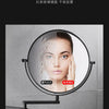 A round folding double-sided wall mirror with telescopic arms showing a close-up of a woman's face.