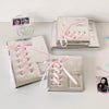 Silver leather photo albums with pink ribbons and star accents displayed on a white surface.