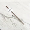 A long, thin metal wand replica with a handle and a decorative tip is displayed on a white marble surface.