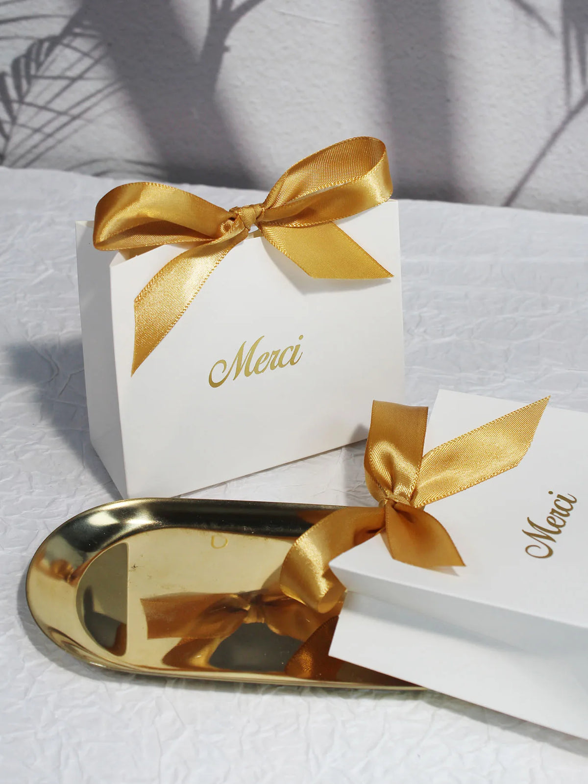 A gold-edged paperboard thank you gift bag tied with a satin ribbon, resting on a white surface.