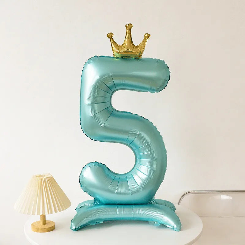 A large, metallic blue foil balloon shaped like the number five with a gold crown on top.