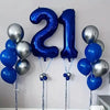 A cluster of large blue and silver foil number balloons spelling '21' for party decoration