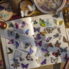 A page of butterfly art collage stickers for scrapbooking featuring various colored and patterned butterflies.