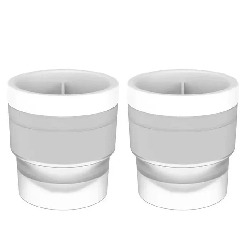 A pair of white stackable spherical ice molds for whiskey and cocktails.