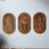 Three oval wooden wall decor pieces featuring delicate dried floral silhouettes in natural wood tones