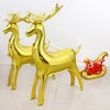 A set of two gold foil balloons shaped like deer standing on a white surface.