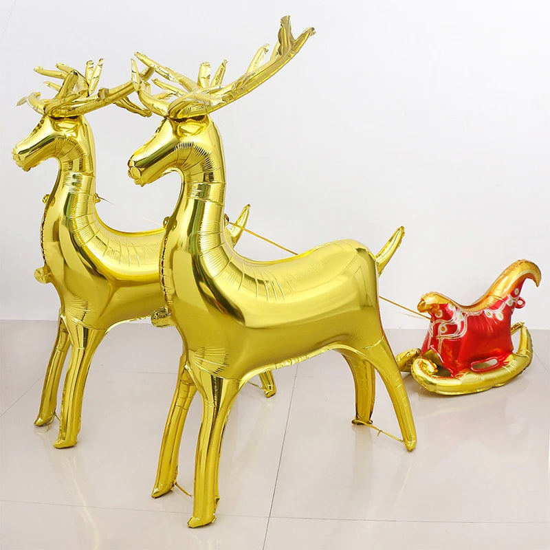 A set of two gold foil balloons shaped like deer standing on a white surface.