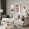 A modern living room features a light sofa, wooden coffee table, and framed art prints on the wall.
