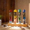 Four glass bottles filled with natural healing stones and zodiac symbols displayed on a wooden surface.