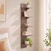 A modern gray vertical wall shelf with five tiers displaying decorative items and plants.