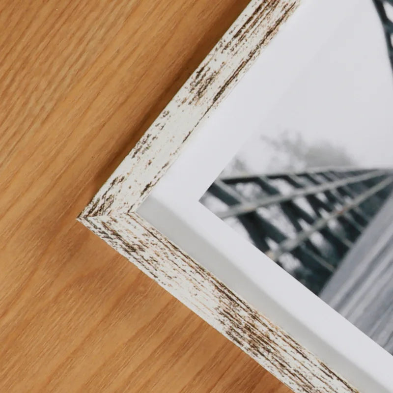 A rustic wooden photo frame with distressed white and brown paint, displaying a blurred outdoor scene.