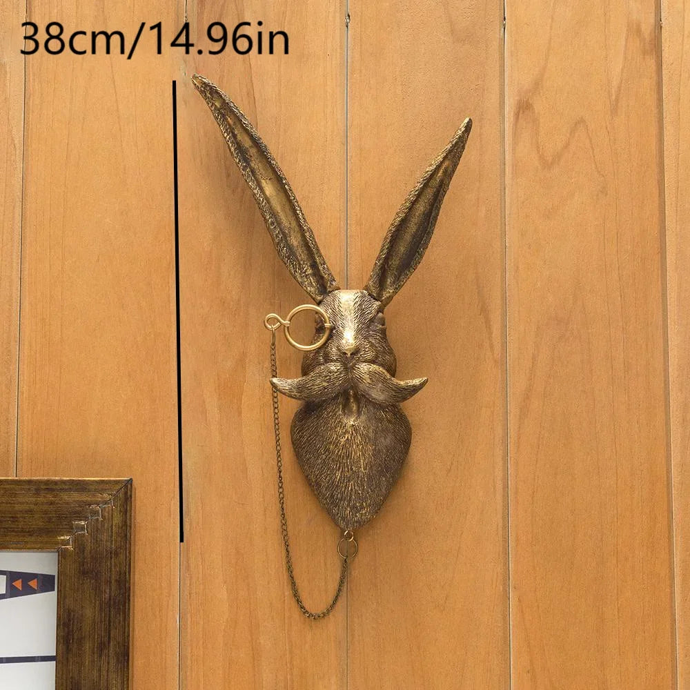 A metallic deer head storage hook wall decor with long ears and a mustache hanging on a wooden panel.