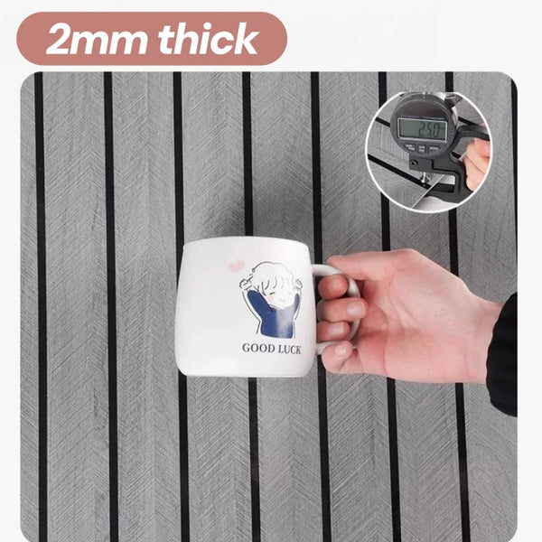 A white mug with the text GOOD LUCK is placed on a gray wooden surface.