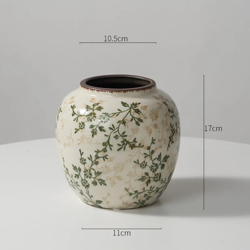 A cream-colored ceramic milk pitcher with a rustic glaze and pastoral green floral design.