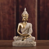 A golden Buddha statue handcrafted from resin sitting in meditation pose on a wooden surface.