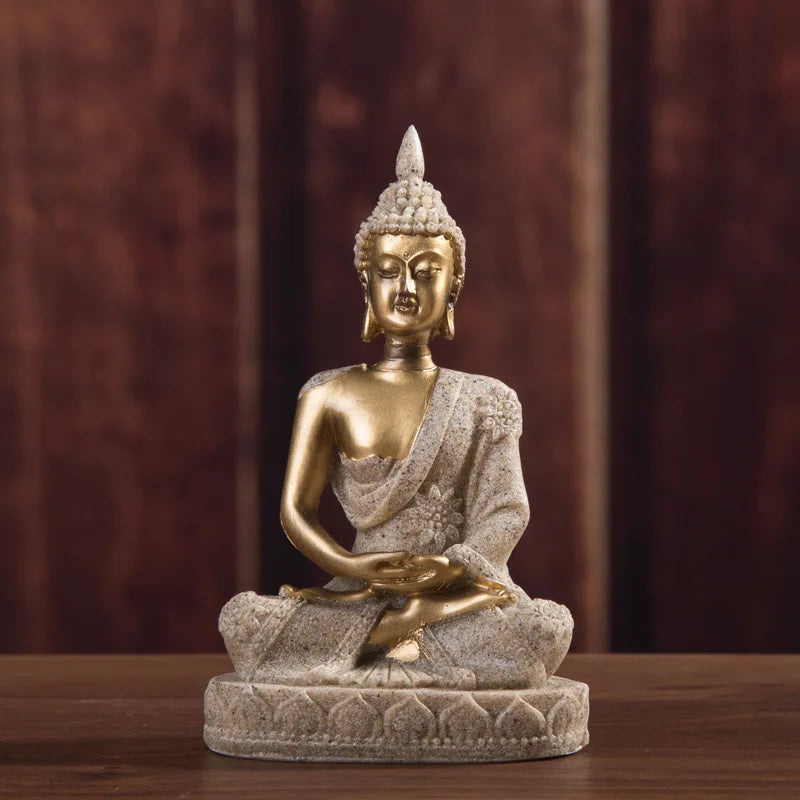A golden Buddha statue handcrafted from resin sitting in meditation pose on a wooden surface.