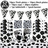A collection of cow print tableware including plates, cups, napkins, a tablecloth, and a banner for a farm-themed party.