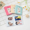A collection of pink, beige, and teal compact photo albums for instant film displayed on a white surface.