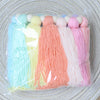 A bundle of colorful yarn strands in pastel shades, including blue, yellow, orange, pink, and white, tied together with woode