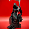 Schwarze Statue einer gotischen Totenfigur mit Sichel vor rotem Hintergrund
