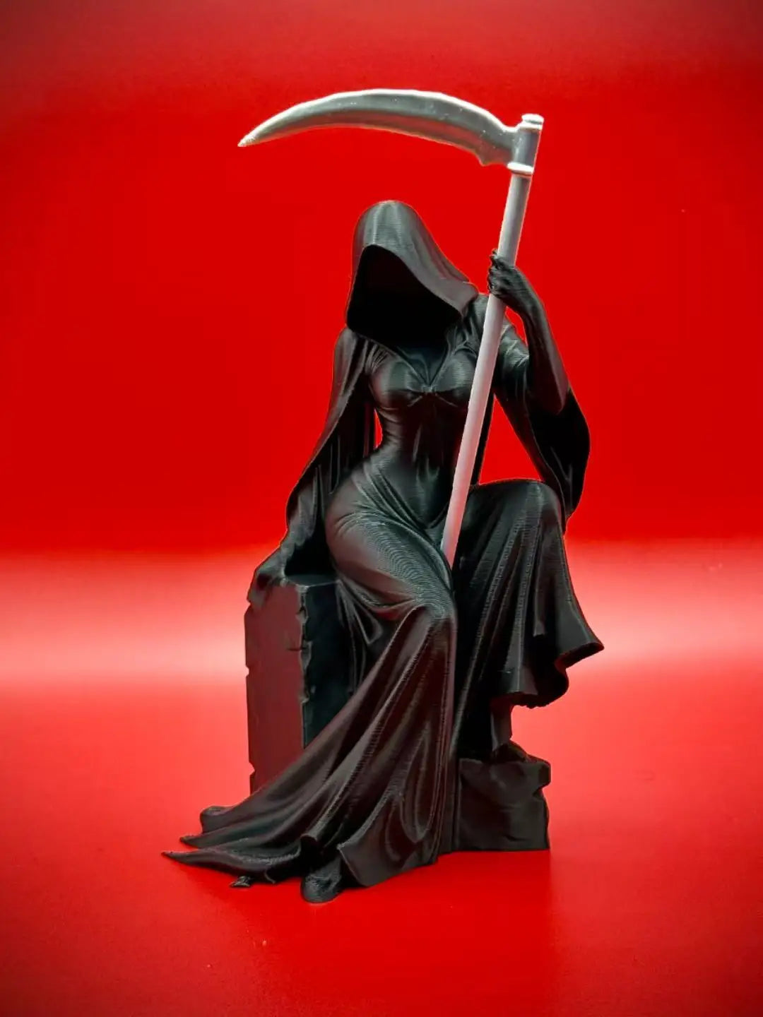 Schwarze Statue einer gotischen Totenfigur mit Sichel vor rotem Hintergrund
