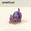 A small, purple crystal figurine shaped like a crouching cat, made by bonding natural crystal fragments with resin.