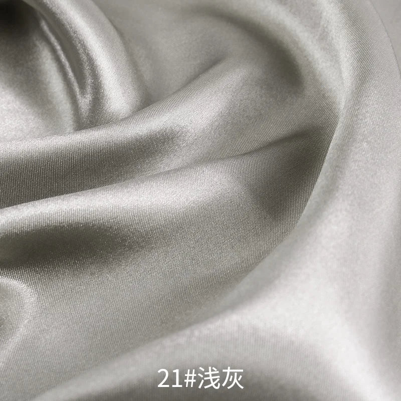 Close-up of smooth, lustrous gray satin fabric draped and folded for sewing or DIY projects.
