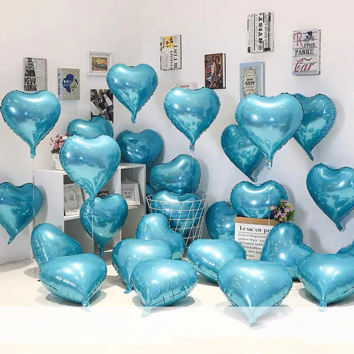 A collection of blue heart foil balloons displayed against a white wall.