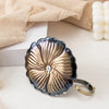 Porte-bougie lotus en fer forgé vintage avec finition martelée sur une surface claire.