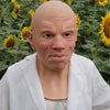 A realistic cute alien full-face latex mask with a bald head and intense expression wearing a white lab coat.