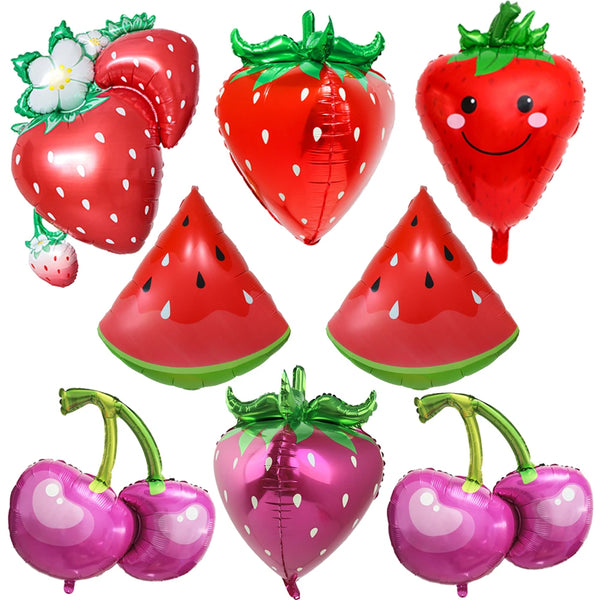 A collection of red and pink fruit-themed party balloons including strawberries, watermelon slices, and cherries.