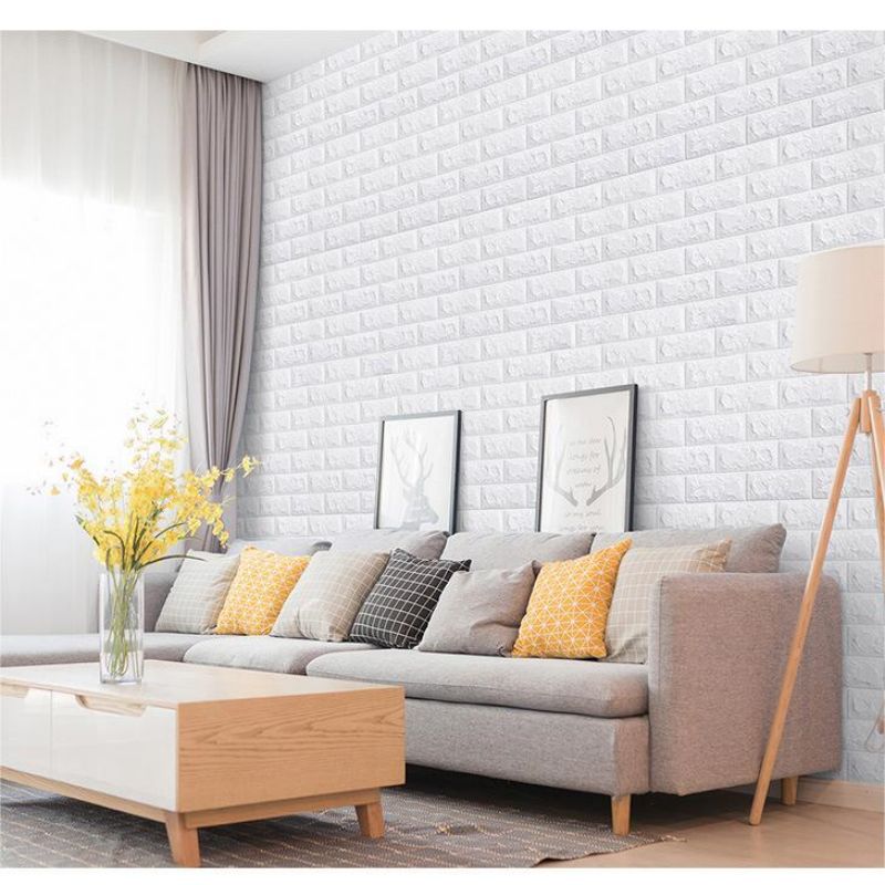 A modern living room featuring a light gray sofa against a white brick wall panel and a wooden coffee table.