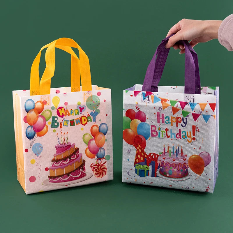 A hand is holding a reusable happy birthday gift bag with colorful balloons and a cake design.