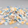 A pile of multicolor paper confetti consisting of light blue, peach, and yellow circular pieces.