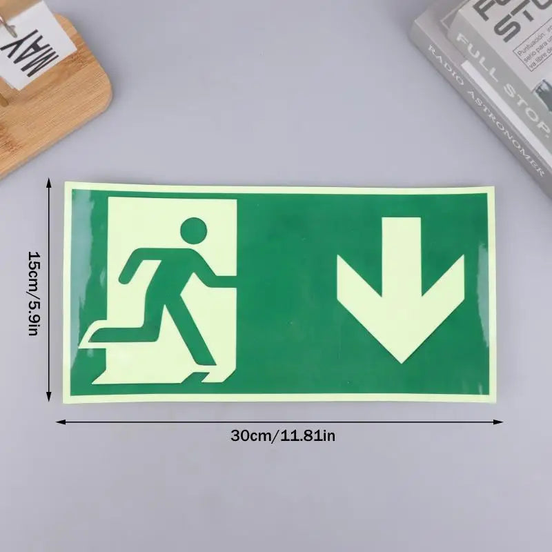 A rectangular photoluminescent emergency exit sign decal showing a silhouette of a person walking and a downward arrow on a g