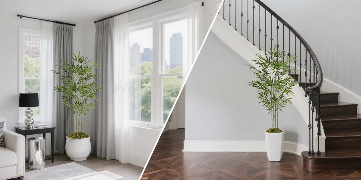 A tall artificial bamboo tree in a white pot displayed on a wooden staircase next to a window.