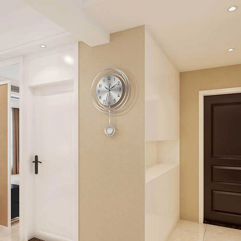 A modern circular wall clock with Arabic numerals is mounted on a beige wall in a hallway.