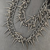 A close-up of a heavy punk rivet biker style necklace made of silver metal spikes and beads.