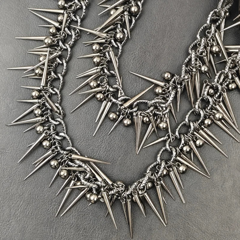 A close-up of a heavy punk rivet biker style necklace made of silver metal spikes and beads.