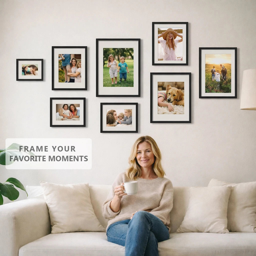 A woman sits on a sofa in front of a wall displaying several framed family photos.
