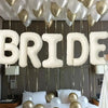 Elegant white and gold balloons suspended from a ceiling above a bed for a bridal theme