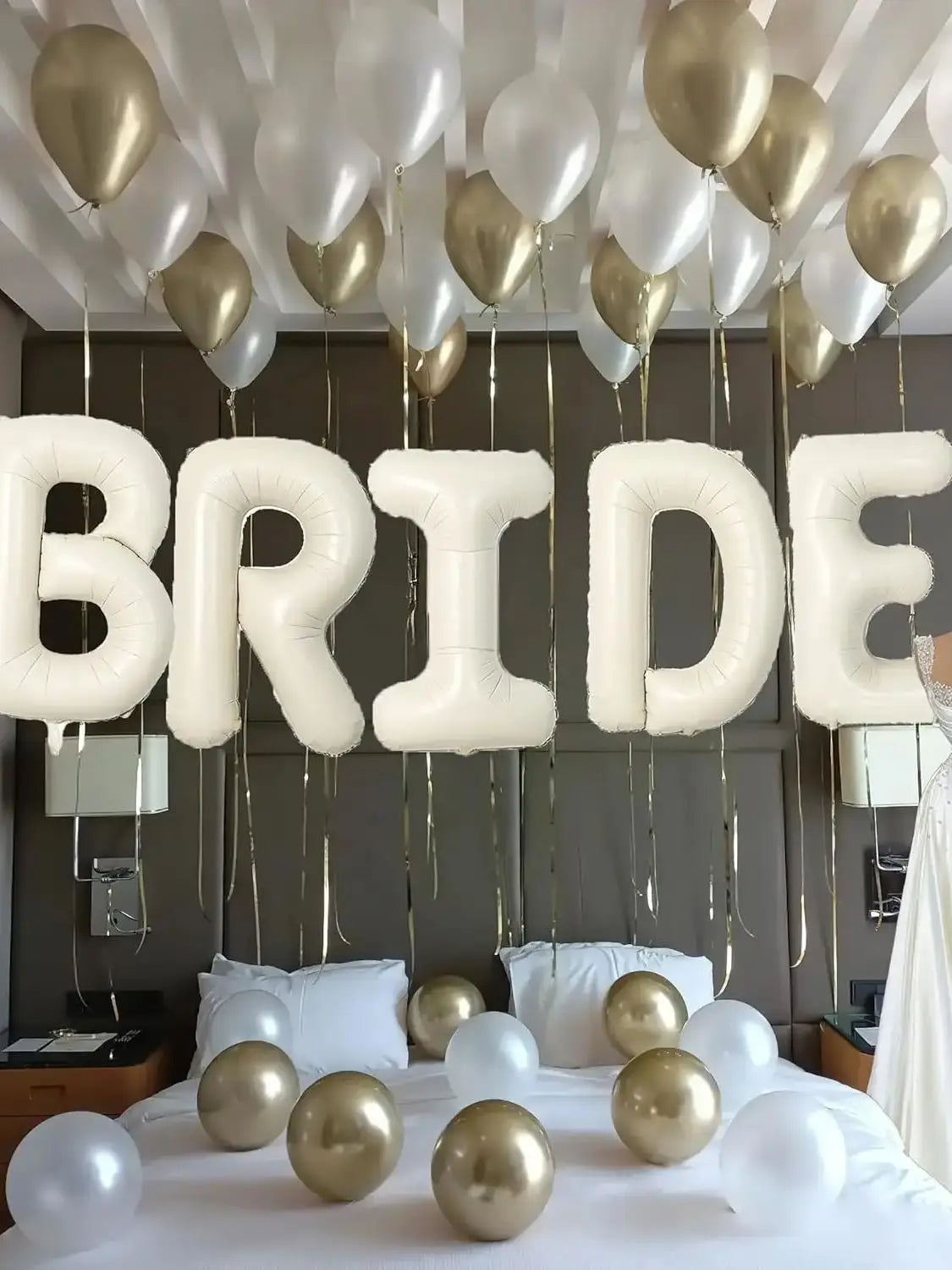 Elegant white and gold balloons suspended from a ceiling above a bed for a bridal theme