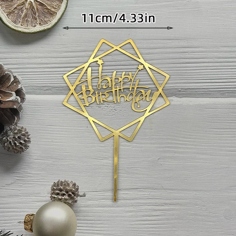 A gold acrylic birthday cake topper featuring the words Happy Birthday in a geometric design on a stick.