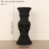 A black plastic skull-shaped vase with a cylindrical body and flared base.