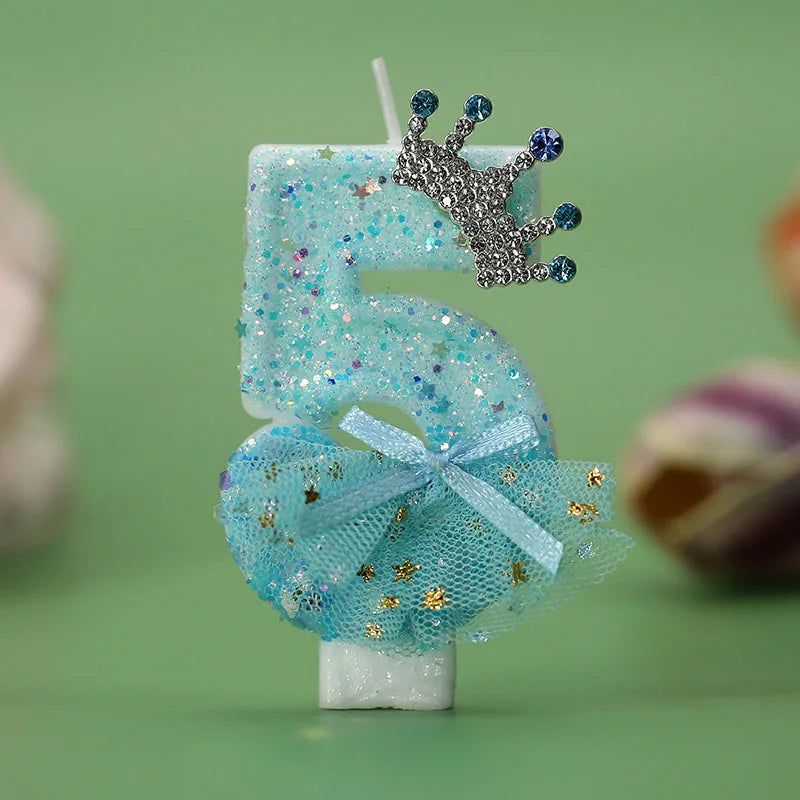 A blue glitter birthday candle decoration shaped like the number 5 with a silver crown topper.